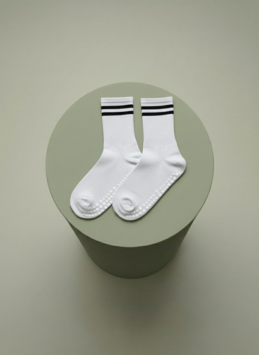 Vita pilates strumpor för träning med halksskydd liggandes på grön cylinder