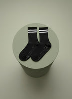 Svarta pilatesstrumpor med vita revärer ligger på grön bakgrund