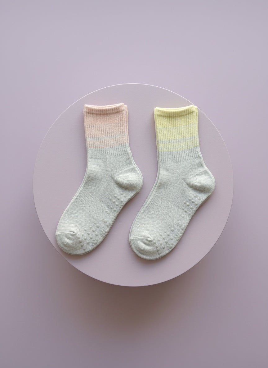 Pilates strumpor med grepp i vit, gul och rosa färg liggandes på rosa bakgrund