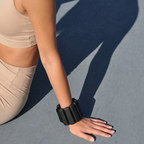 kvinna som sitter på marken med svarta ankle weights för pilates på armen