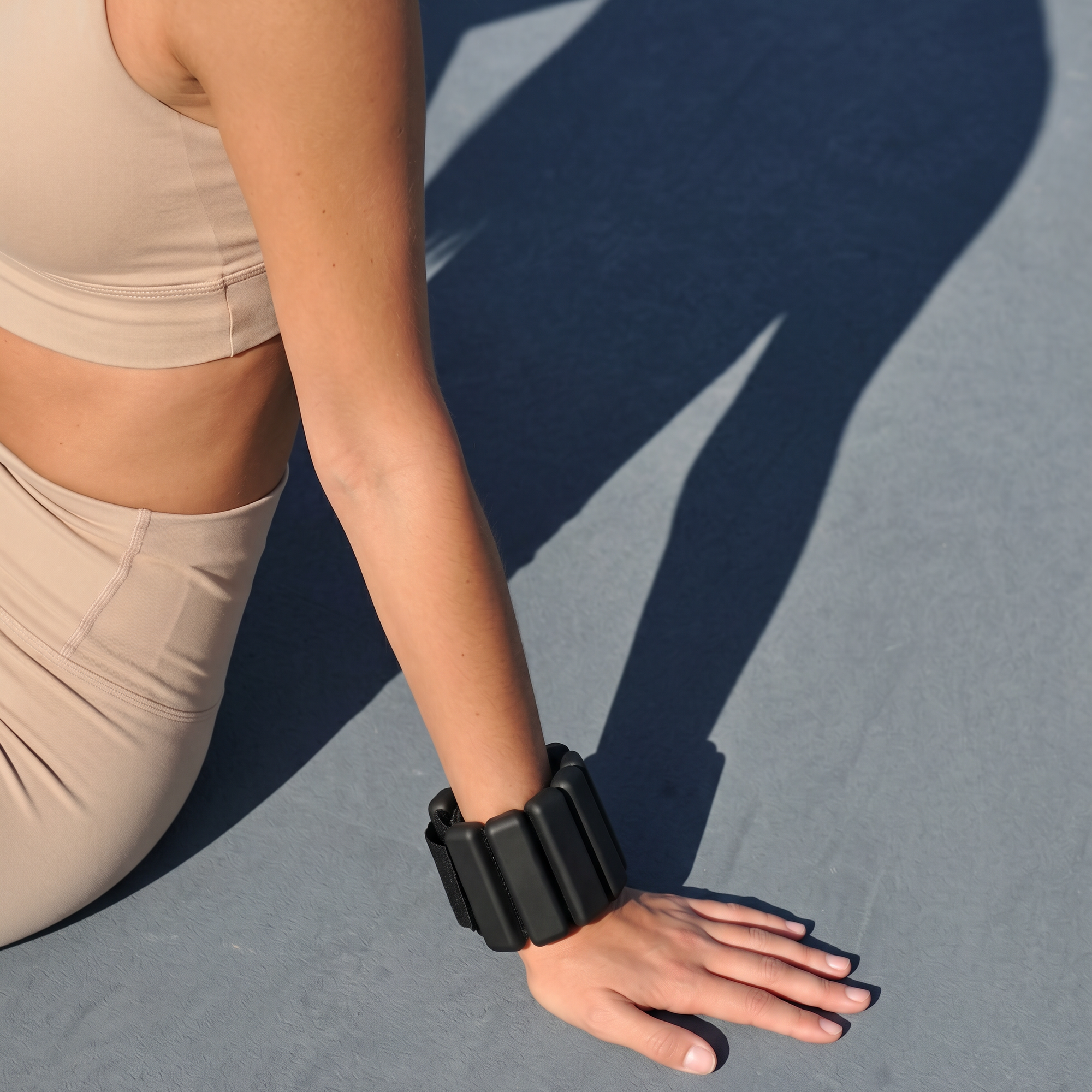 kvinna som sitter på marken med svarta ankle weights för pilates på armen
