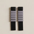 grå pilates vikter för ankel och handled med svart straps liggandes på beigt golv