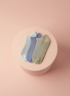 Låga pilates strumpor för yoga i vit, lila och beige liggandes på beige bakgrund