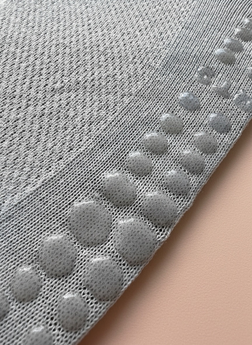 Närbild på undersidan av en grå strumpa för pilates där man ser att strumpan har grepp