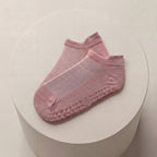 pilates ankelstrumpor i rosa mot beige bakgrund liggandes på varandra