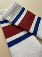 nära bild tagen på ett par vit röd blå pilates strumpor på en beige bakgrund