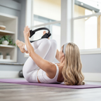 blond kvinna i vita träningskläder använder pilatesring på yogamatta