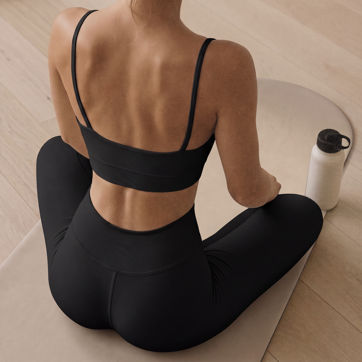 woman in black clothes sitting on pilates mat