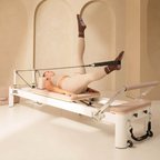 woman wearing brown pilates grip socks doing workout on reformer machine in a beige room