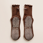 undersida av bruna grip socks med vitt grepp liggandes mot vit bakgrund
