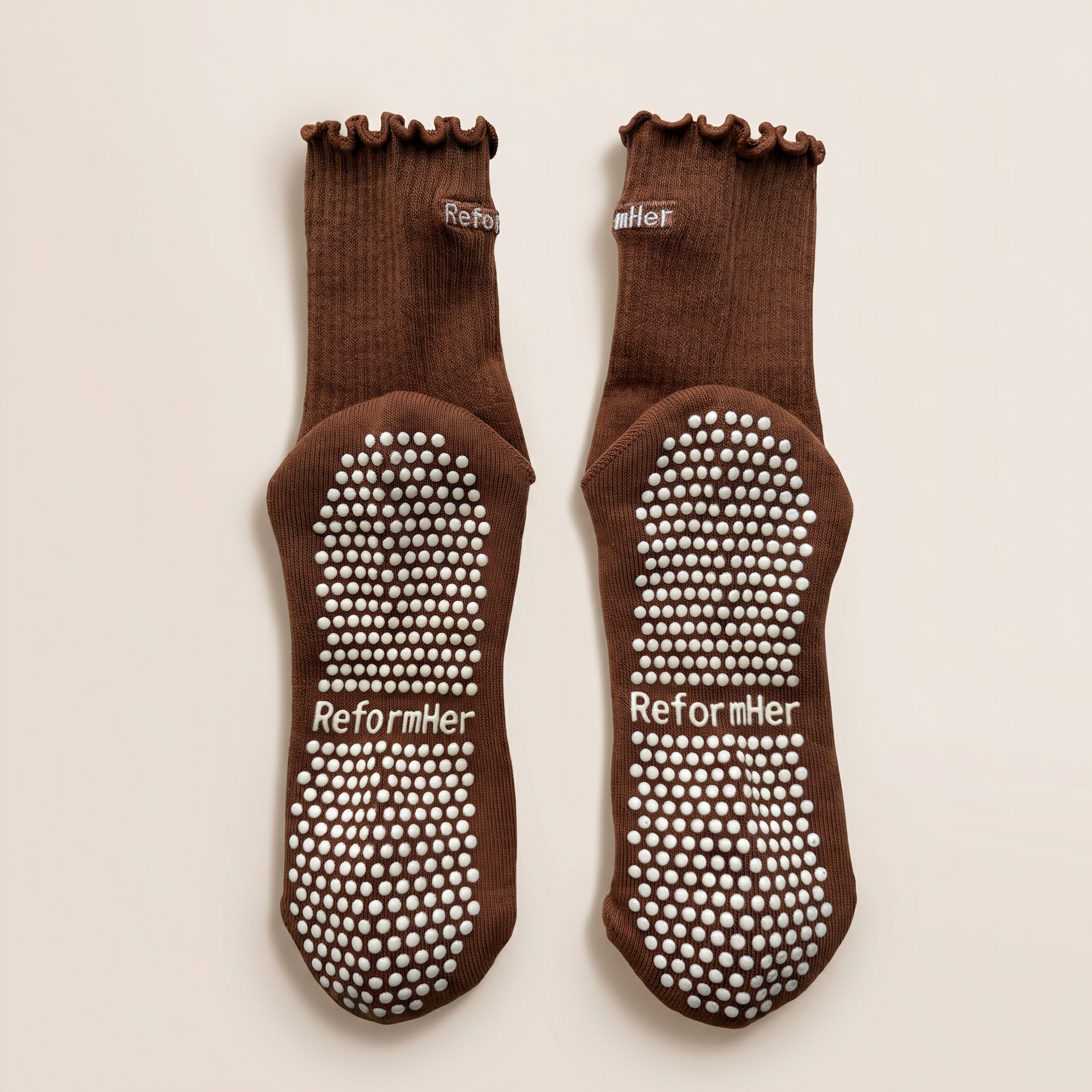 undersida av bruna grip socks med vitt grepp liggandes mot vit bakgrund