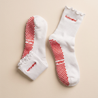 vita och röda pilates grip socks mot beige bakgrund