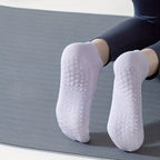 Kvinna som gör pilates övning iförd ett par vita pilates strumpor med grepp under strumpan 