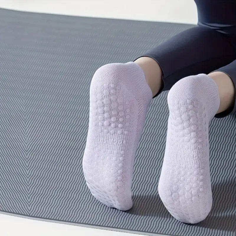 Kvinna som gör pilates övning iförd ett par vita pilates strumpor med grepp under strumpan 