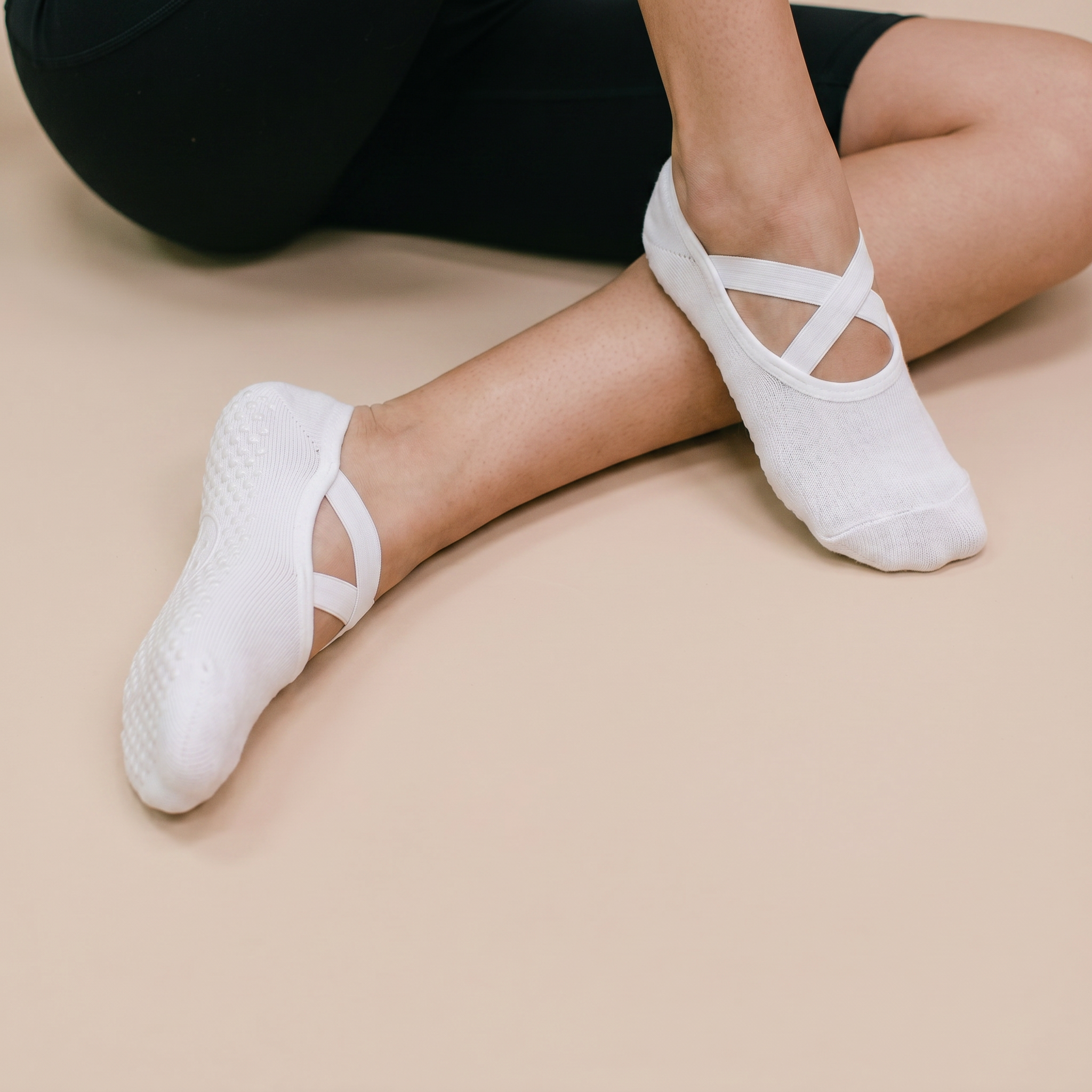 kvinna bär vita greppstrumpor för pilates mot beige golv