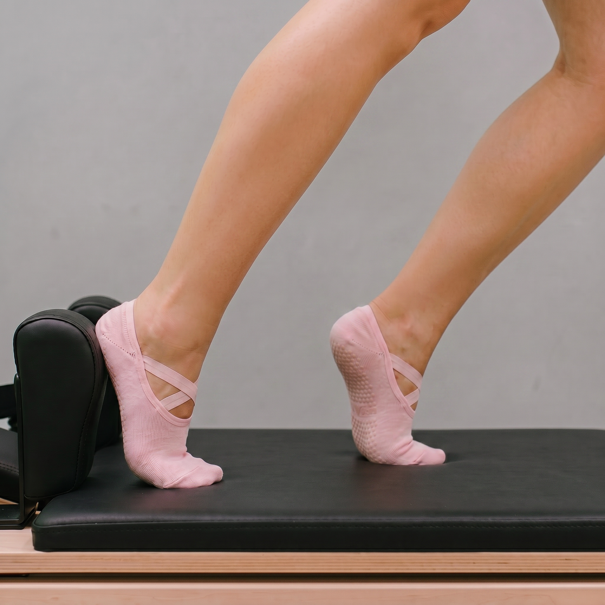 kvinna på reformer maskin gör övning i rosa greppstrumpor för pilates