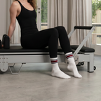 zoomed i. image of woman sitting on pilates machine in white grip socks